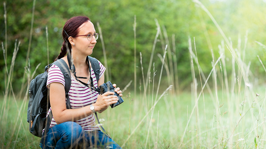 eine Frau mit Feldstecher in einem Feld